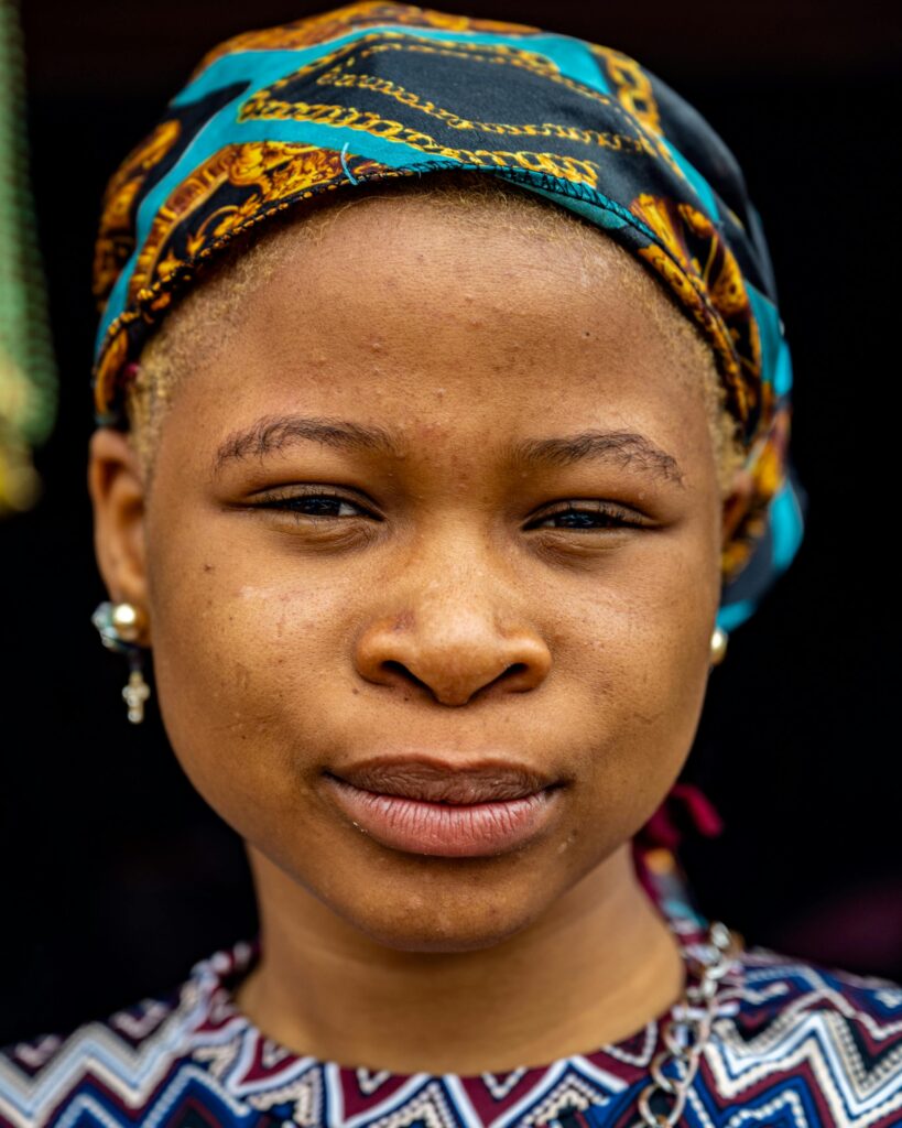 Close-up portrait of an African woman wearing a colorful patterned headscarf in Osun, Nigeria.